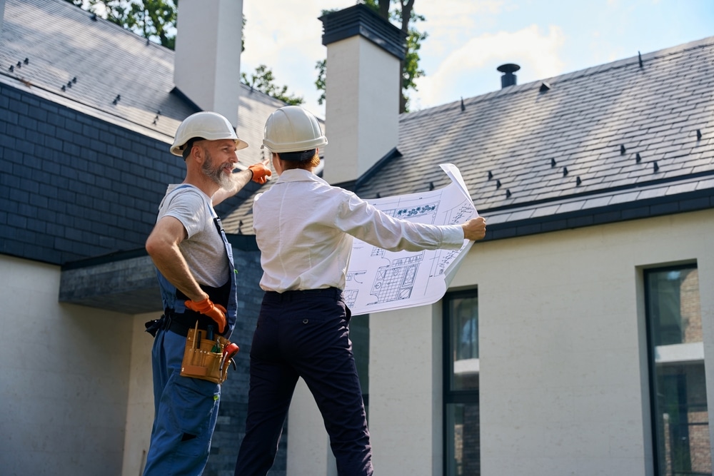 Top-Quality Roofing Solutions. Pleased contractor demonstrating cottage facade to construction manager.