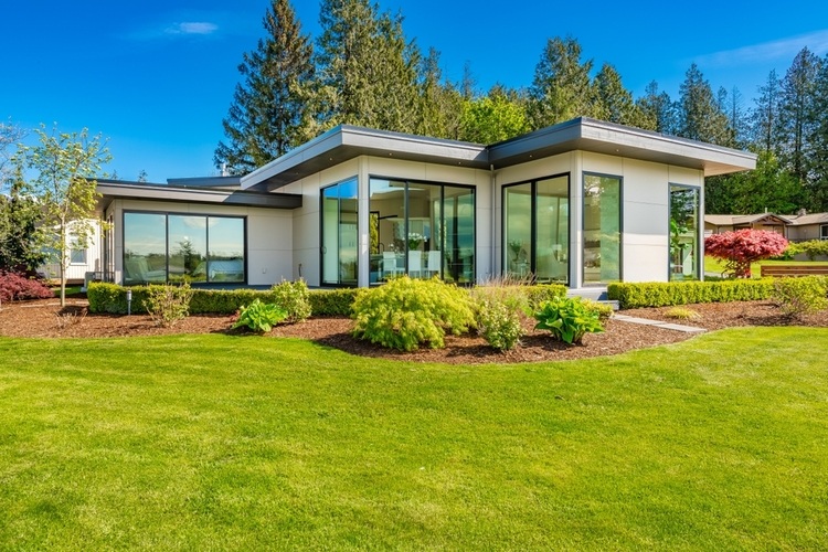 Flat Roofing Services in Ottawa: What Homeowners Need to Know. Contemporary home exterior on lakeshore with flat roof and large feature windows.