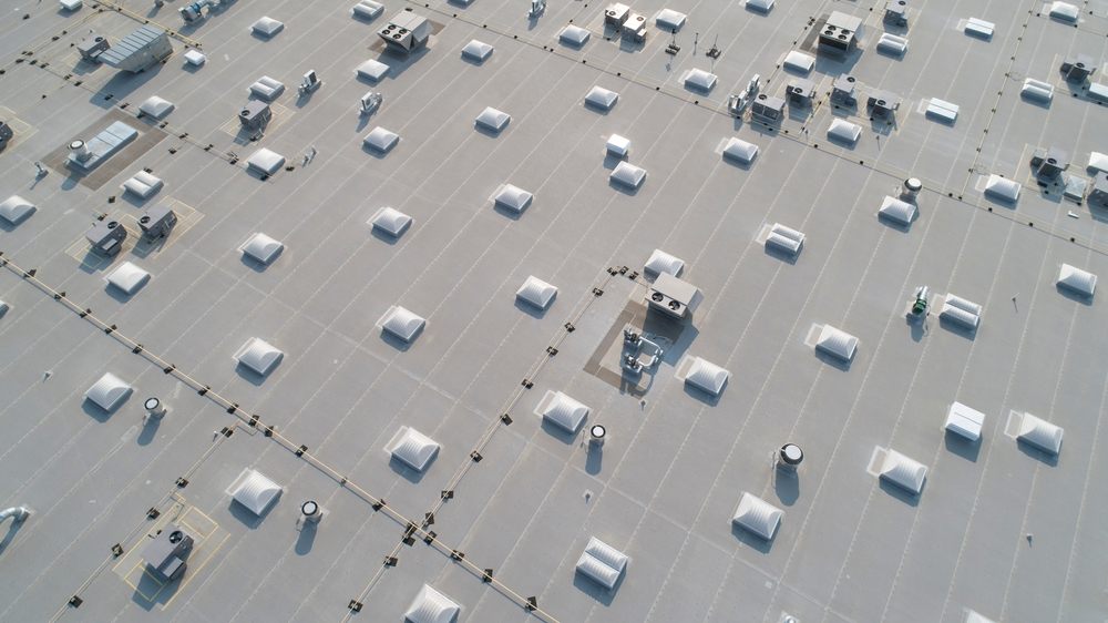 Why Choose Stewart Roofing for Commercial Roof Repair in Ottawa: A Trusted Local Solution. Aerial view of skylights and HVAC equipment on top of a commercial roof building.